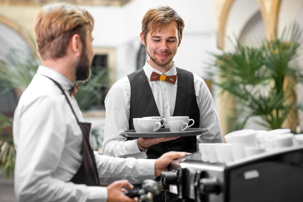 Barista making coffee with waiter