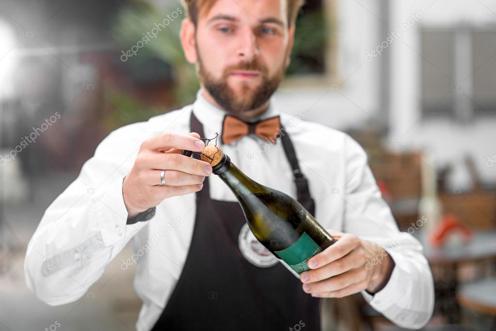 Barman opening bottle with sparkling wine
