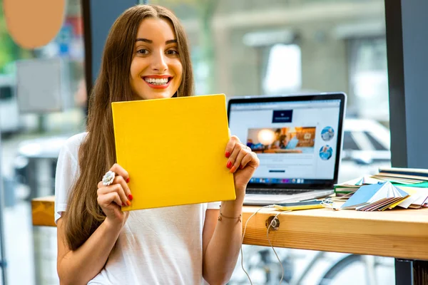 Young female student holding yellow book — Stockfoto