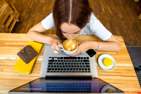 Woman enjoying cappuccino sitting with laptop — ストック写真