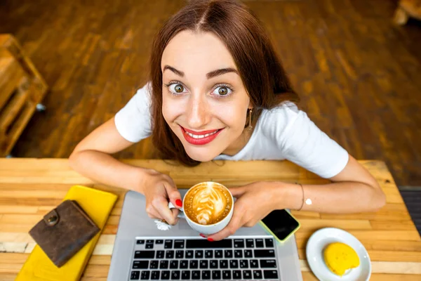 Woman enjoying cappuccino sitting with laptop — Stok fotoğraf