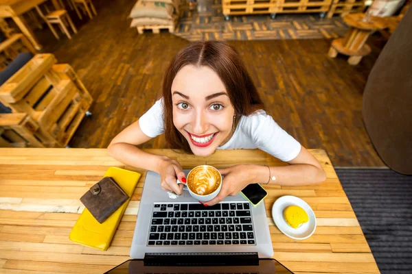 Woman enjoying cappuccino sitting with laptop — Stock fotografie