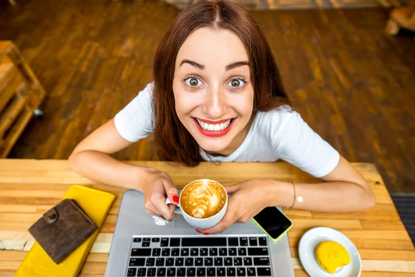 Woman enjoying cappuccino sitting with laptop — Stock Photo, Image