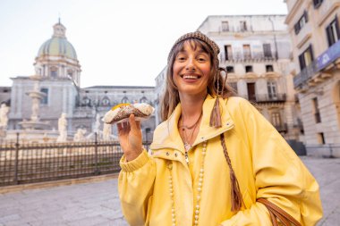 Palermo, İtalya 'nın tarihi merkezinde geleneksel Sicilya Cannolo' sunu tutan gülümseyen kadın. Neşeli seyahat anı ve otantik yerel deneyim