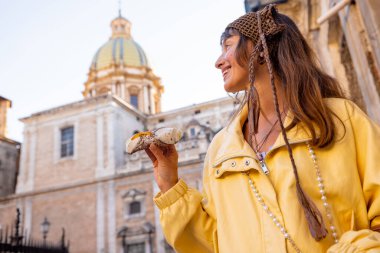 Palermo, İtalya 'nın tarihi merkezinde geleneksel Sicilya Cannolo' sunu tutan gülümseyen kadın. Neşeli seyahat anı ve otantik yerel deneyim