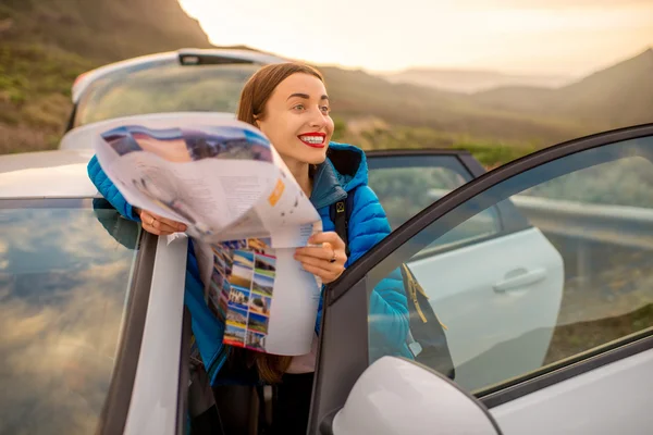 Женщина-путешественница с туристической картой рядом с автомобилем — стоковое фото