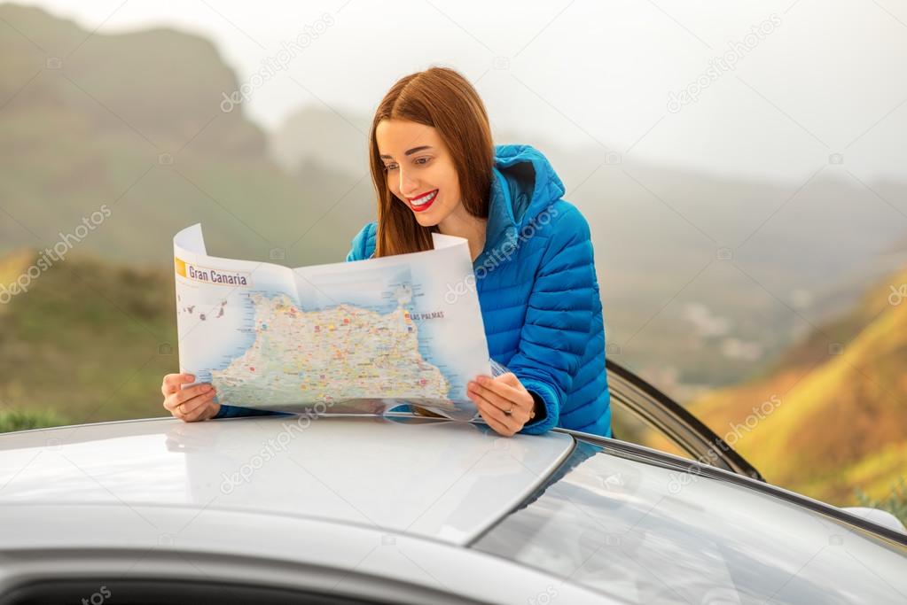 Female traveler with toursit map near the car