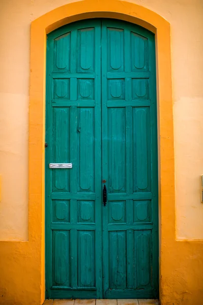 Zielone drzwi w ścianie żółty — Zdjęcie stockowe