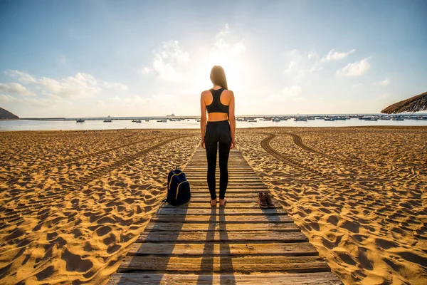 Mulher de roupas esportivas pretas em pé na praia — Fotografia de Stock