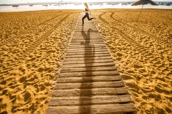Sandstrand mit Schatten von laufender Frau — Stockfoto