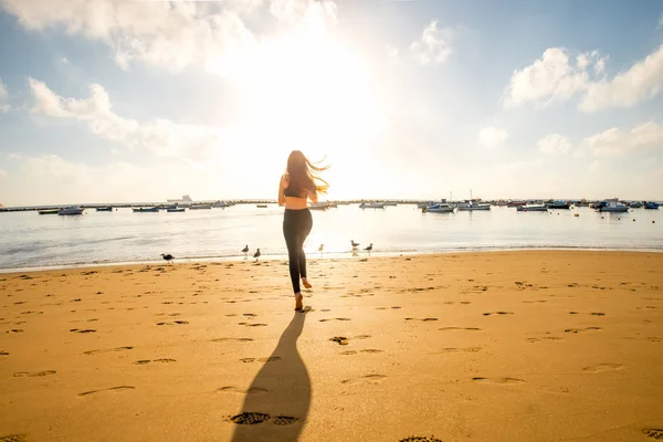 Женщина бежит по песчаному пляжу — стоковое фото