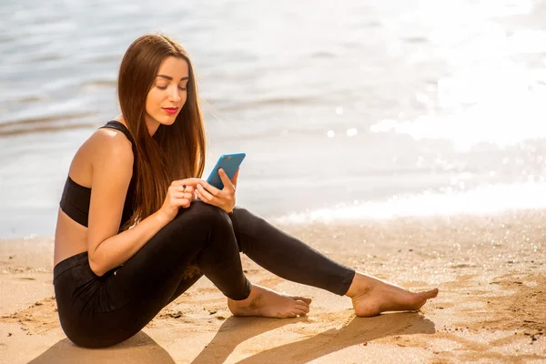 Femme avec smartphone sur la plage — Photo