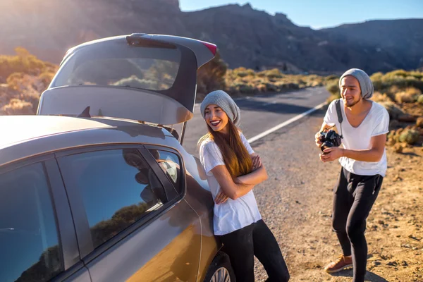 Jóvenes viajeros de pareja divirtiéndose cerca del coche — Foto de Stock