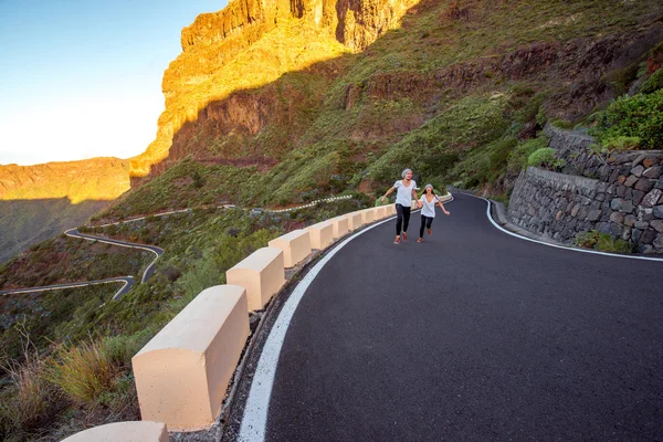 Carefree couple running on the mountain roadside — Stock Photo, Image