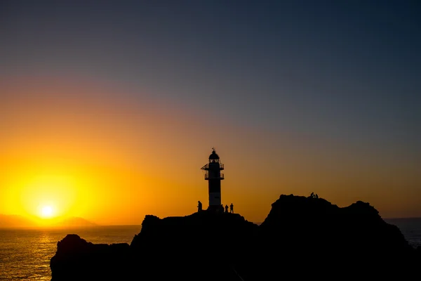 Скалистое побережье с маяком на закате — стоковое фото