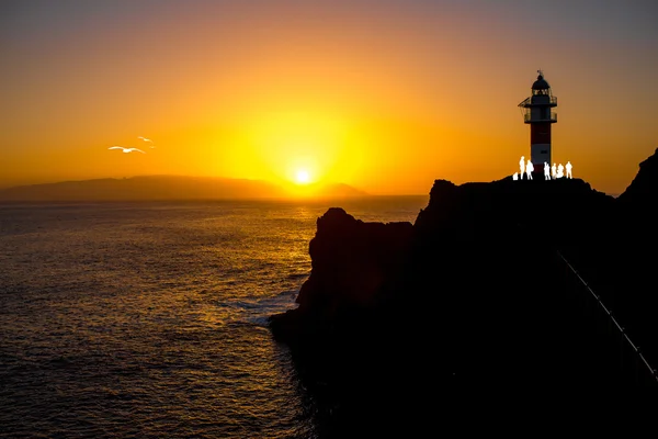 Silhuetas de pessoas perto do farol — Fotografia de Stock