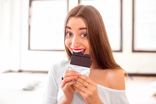 Woman eating black chocolate in the gym — Stock Photo, Image
