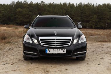Dnipro, Ukrayna - 21 Kasım 2020: Mercedes-Benz E220 CDI 2011 sonbahar şehrinde orman yakınlarındaki siyah renk