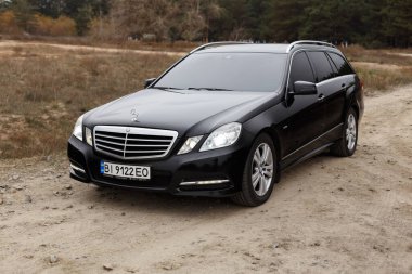 Dnipro, Ukrayna - 21 Kasım 2020: Mercedes-Benz E220 CDI 2011 sonbahar şehrinde orman yakınlarındaki siyah renk