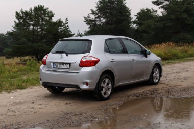 Dnipro, Ukrayna - 30 Temmuz 2021: Toyota Auris 2012 Orman yakınlarındaki şehirde gümüş rengi. Yaz yağmuru