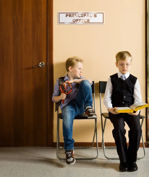 Schoolboys are sitting beside the principals office in school — Stock Photo, Image