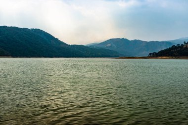 lake calm water with mountain background at day from flat angle image is taken at umiam lake shillong meghalaya india.
