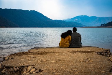 young couple holding each other and looking the serene natural beauty at day from flat angle