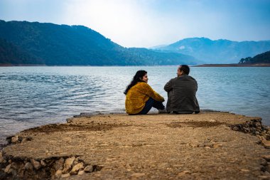 young couple talking with each other with serene natural beauty at day from flat angle