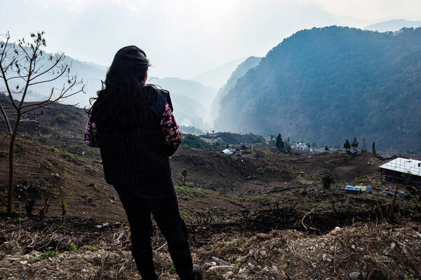 young girl watching the misty mountain valley with sun rays beams at morning from flat angle