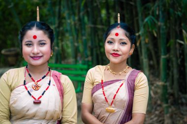 Festivalde geleneksel giyinmiş gülümseyen kızlar Assam Hindistan 'da Bihu vesilesiyle arka planda bulanık bir resim çekiliyor..