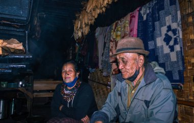 Apatani kabilesi çifti akşam yemeği pişirmek için şöminenin yanındaki evlerinde Ziro Arunachal Pradesh Hindistan 'da çekiliyor. Hindistan 'ın en eski kabilesinden biri..