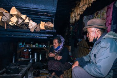 Apatani kabilesi çifti akşam yemeği pişirmek için şöminenin yanındaki evlerinde Ziro Arunachal Pradesh Hindistan 'da çekiliyor. Hindistan 'ın en eski kabilesinden biri..