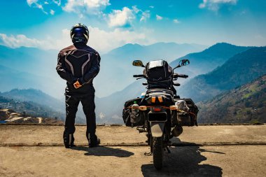 Motosikletli bir adam dolu motosikleti ve el değmemiş doğal görüntüsüyle tepede duruyor. Bombdila Arunachal Pradesh Hindistan 'da çekildi..