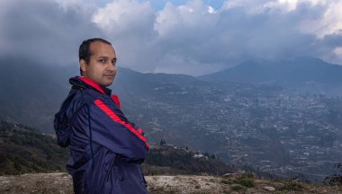 Akşamları dramatik gökyüzü ile dağın tepesinde duran bir adam