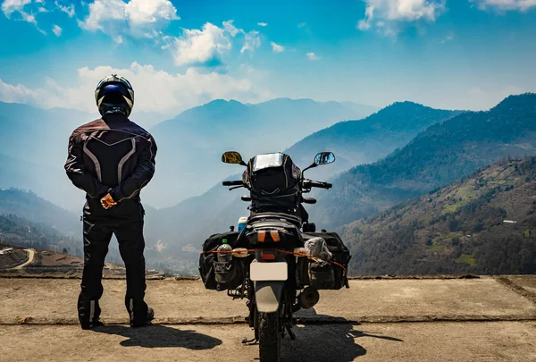 Motosikletli bir adam tepeden vadiyi seyrediyor. Yüklü motosikleti ve el değmemiş doğal görüntüsüyle Bombdila Arunachal Pradesh Hindistan 'da çekildi..