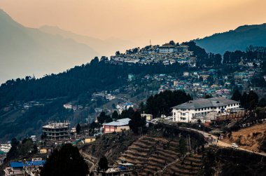 Tawang şehir manzarası tepenin üstünde turuncu gökyüzü ile akşam görüntüsü dev Buda heykeli Tawang Arunachal Pradesh Hindistan 'da çekilmiştir..