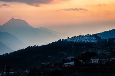 Tawang antik Budist manastırı manzarası, turuncu gökyüzü ve dağ gölgesi ile akşam üstü dev Buda heykeli Tawang Arunachal Pradesh Hindistan 'da çekilmiştir..