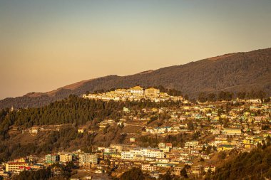 Tawang şehir manzarası tepenin üstünde turuncu gökyüzü ile akşam görüntüsü dev Buda heykeli Tawang Arunachal Pradesh Hindistan 'da çekilmiştir..