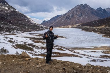 Donmuş gölde tek başına gezen genç adam, dağ vadisi geçmişine sahip. Görüntü sela pass tawang arunachal pradesh India 'dan alınmıştır..