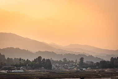 Dağ eteklerinde köy ve şafak vakti portakal rengi gökyüzü olan dağ katmanları Ziro Arunachal Pradesh Hindistan 'da çekiliyor..