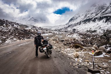 Dişlileri dolu bir motosikletle ıssız bir yolda ve karla kaplı dağlarda tek başına gezen adam sela pass tawang arunachal pradesh 'te görüntülenir..