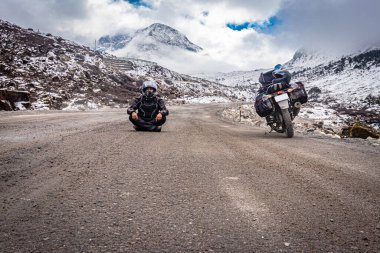 İzole edilmiş asfalt yolda tek başına gezen bir adam ve arka planda kar örtüsü dağları ile sabah görüntüsü Tawang Arunachal Pradesh Hindistan 'da çekilmiştir..