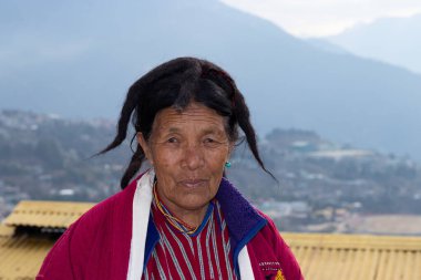 Monpa kabilesinin geleneksel elbise portreleri içinde yaşlı bir kadın detaylarla kapanıyor.