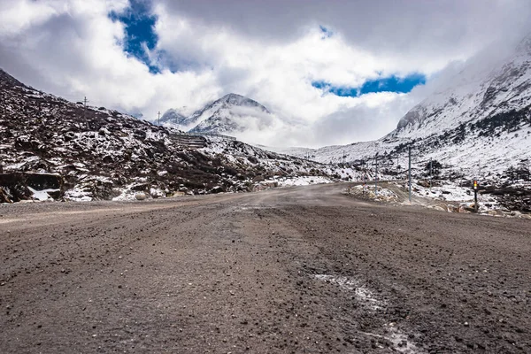 Απομονωμένη Άσφαλτος Δρόμος Χιόνι Καπάκι Φόντο Βουνό Και Εκπληκτικό Ουρανό — Φωτογραφία Αρχείου