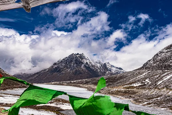 昼のイメージで仏教の旗のフレームを通して劇的な空を持つ雪の山はセラ タワン アラナカル プラデーシュ インディアで撮影されました — ストック写真
