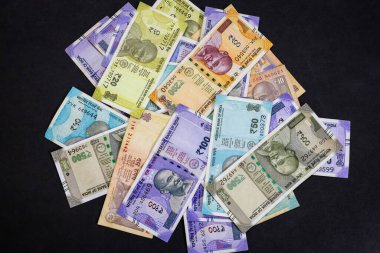 Siyah arka planda bir yığın renkli Hint Rupisi.