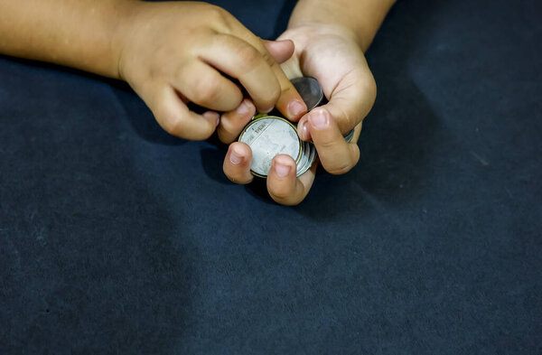 Small hand interacting with Indian coins illustrating growth in money handling skills