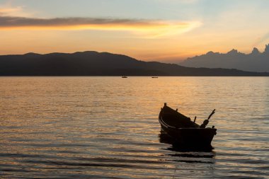 Gün batımında sakin denizde yüzen sakin bir tekne.