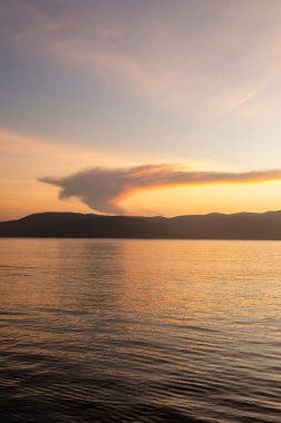 Sakin suların üzerinde parlayan ufuk ve akşam günbatımında tekneler.