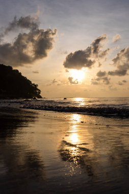 Sakin kıyı şeridinde dramatik bir gün doğumu ve dağınık sahil kayaları.